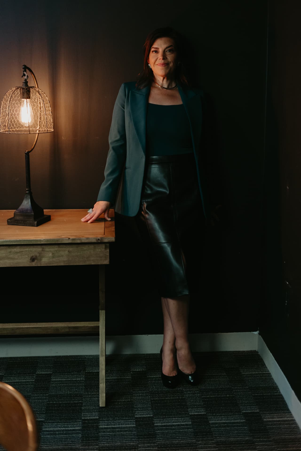Kellena standing in a darkened room beside a small lit table lamp